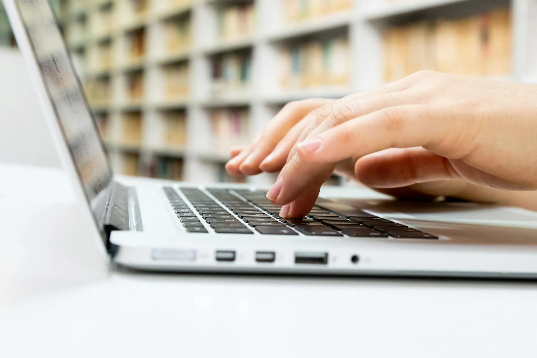 Pessoa usando computador com interface de busca acadêmica moderna, cercada de livros e artigos científicos