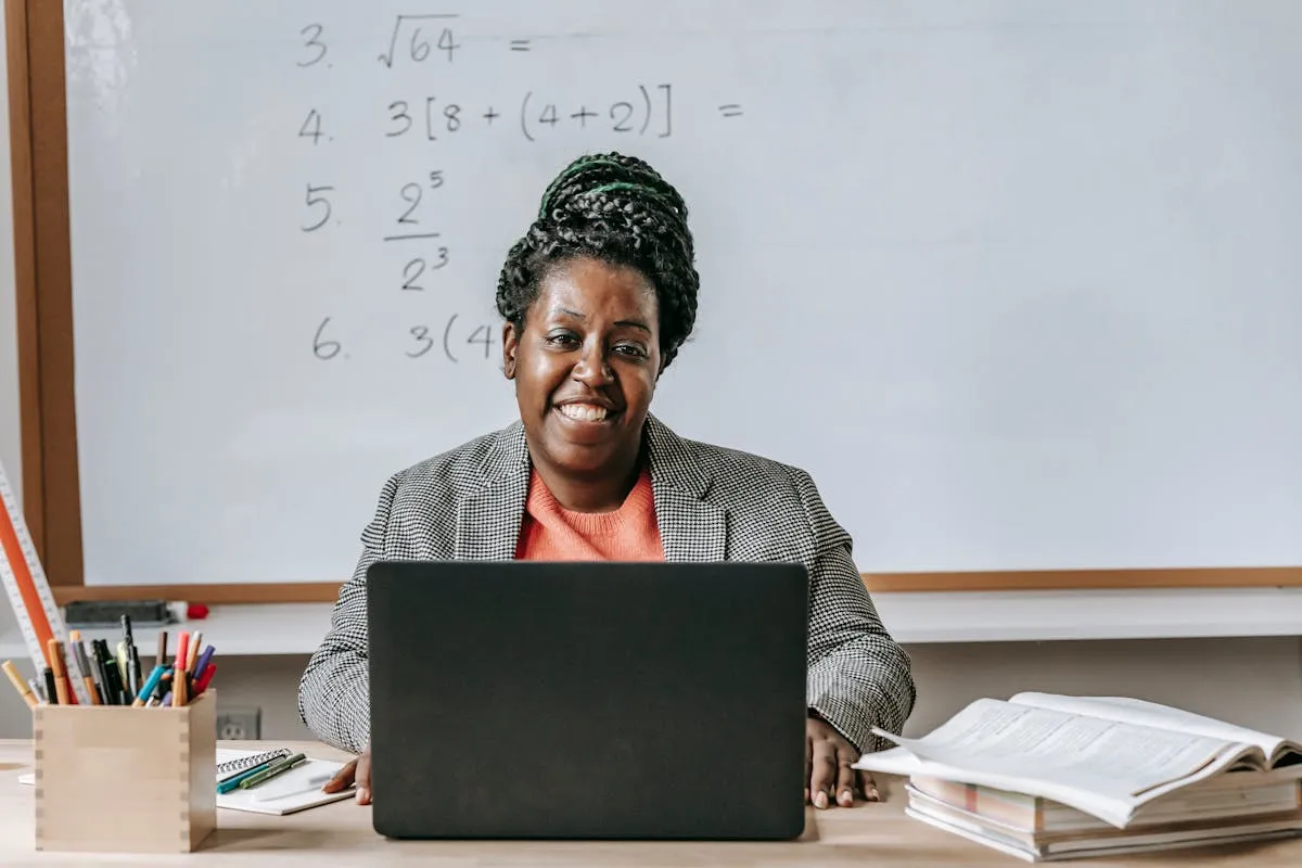 Professora criando material didático no computador com notas e referências ao redor