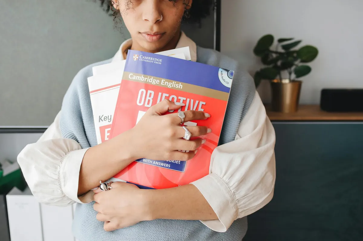 Pessoa estudando inglês com livros e cadernos abertos em mesa de trabalho