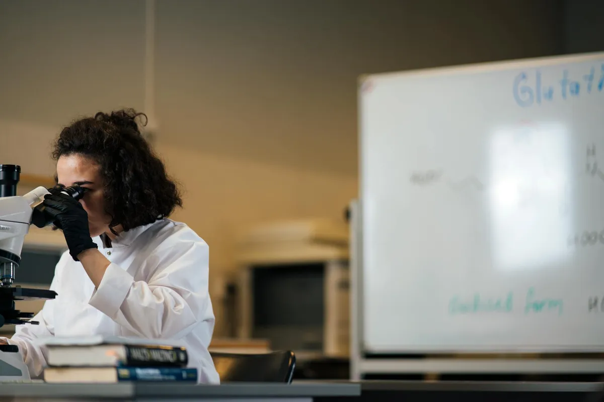 Estudante de graduação trabalhando em laboratório de pesquisa com orientação de professor