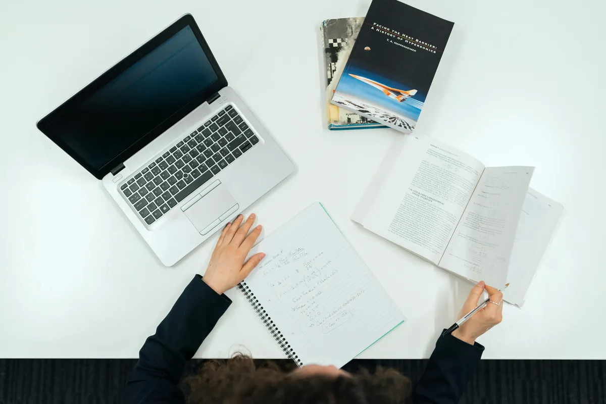 Profissional de negócios estudando materiais acadêmicos em mesa de trabalho organizada