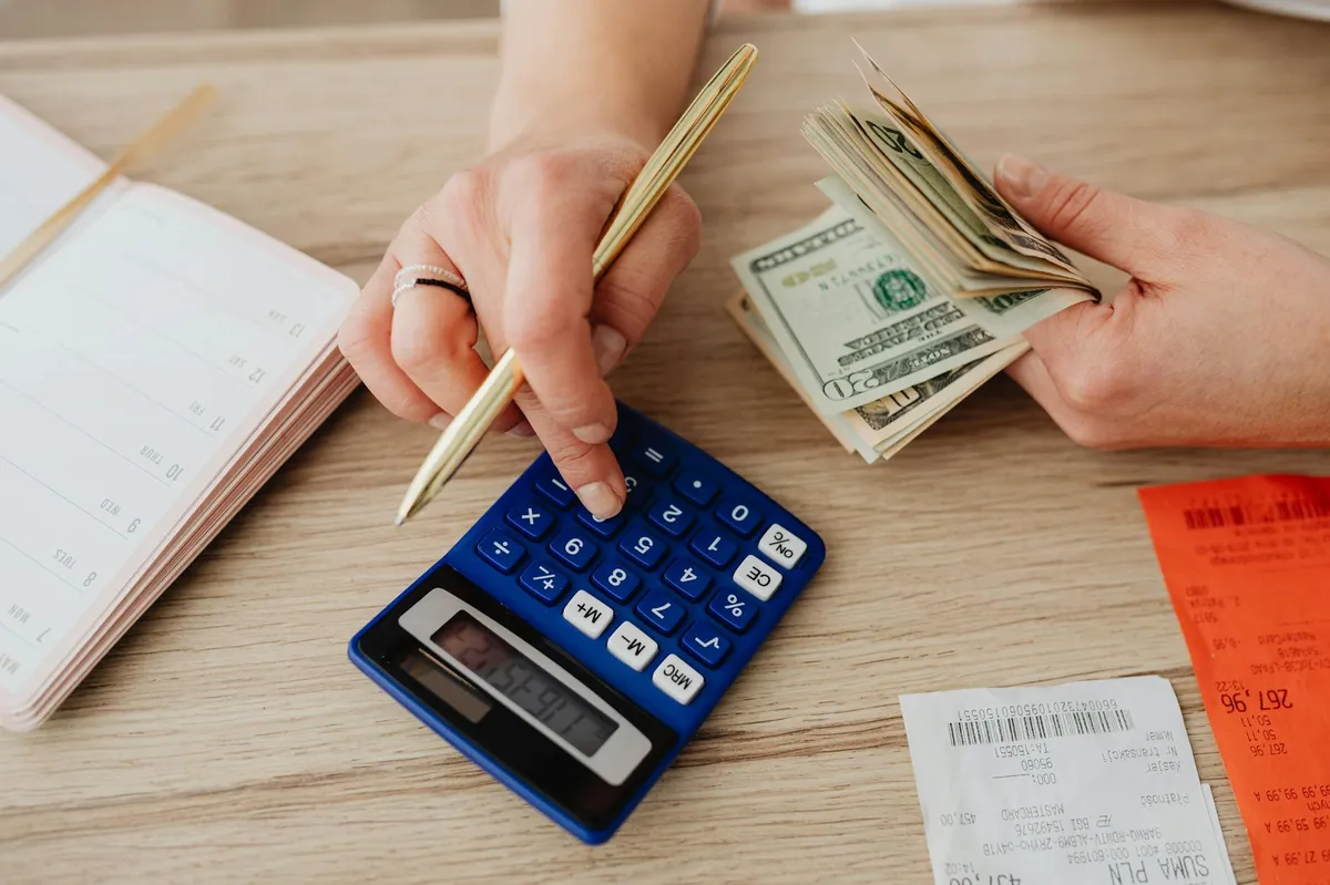Pessoa fazendo cálculos financeiros com calculadora e caderno em mesa