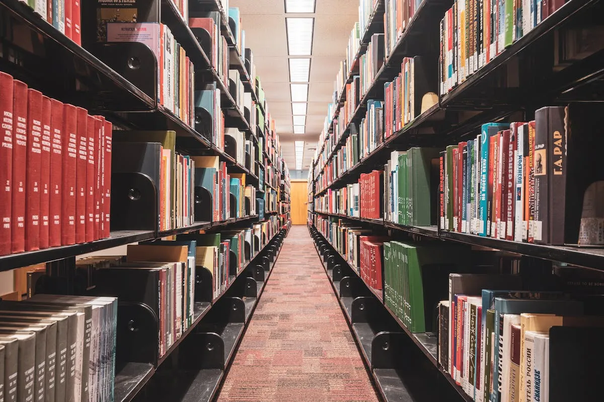 Livros acadêmicos empilhados sobre mesa de madeira representando diferentes tipos de trabalho científico