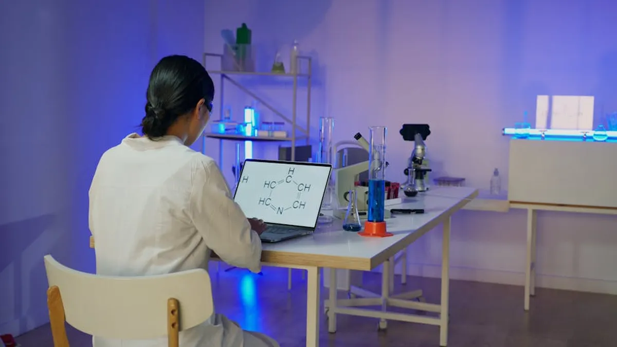 Pesquisador em laboratório de química usando computador com modelos moleculares na tela
