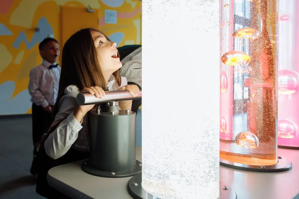 Crianças explorando exposição interativa de ciências em um museu, tocando em modelos e experimentos