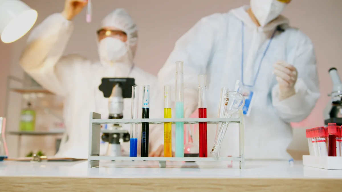 Frascos de laboratório com extratos de plantas medicinais ao lado de equipamento de pesquisa científica