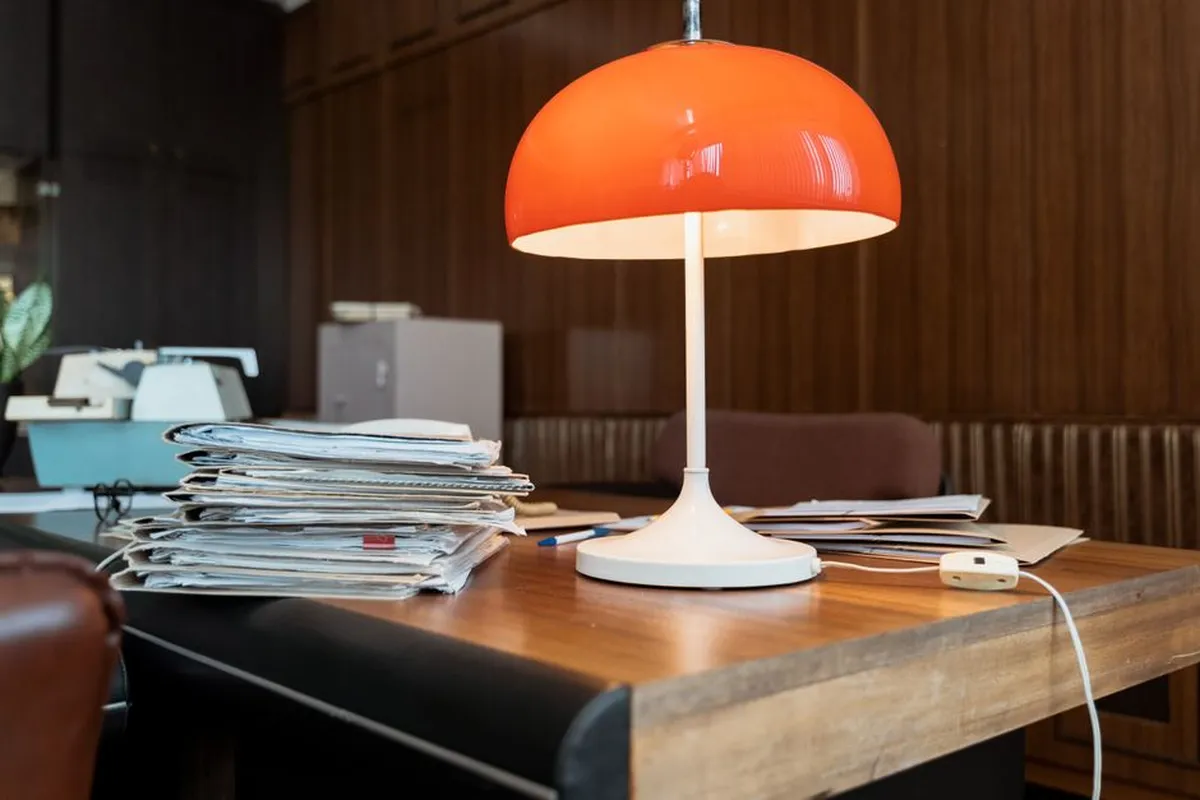 Mesa de trabalho com pilha de papéis e um computador, sugerindo sobrecarga