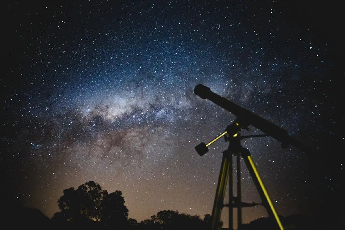 Telescópio refletor apontado para o céu estrelado durante observação astronômica noturna