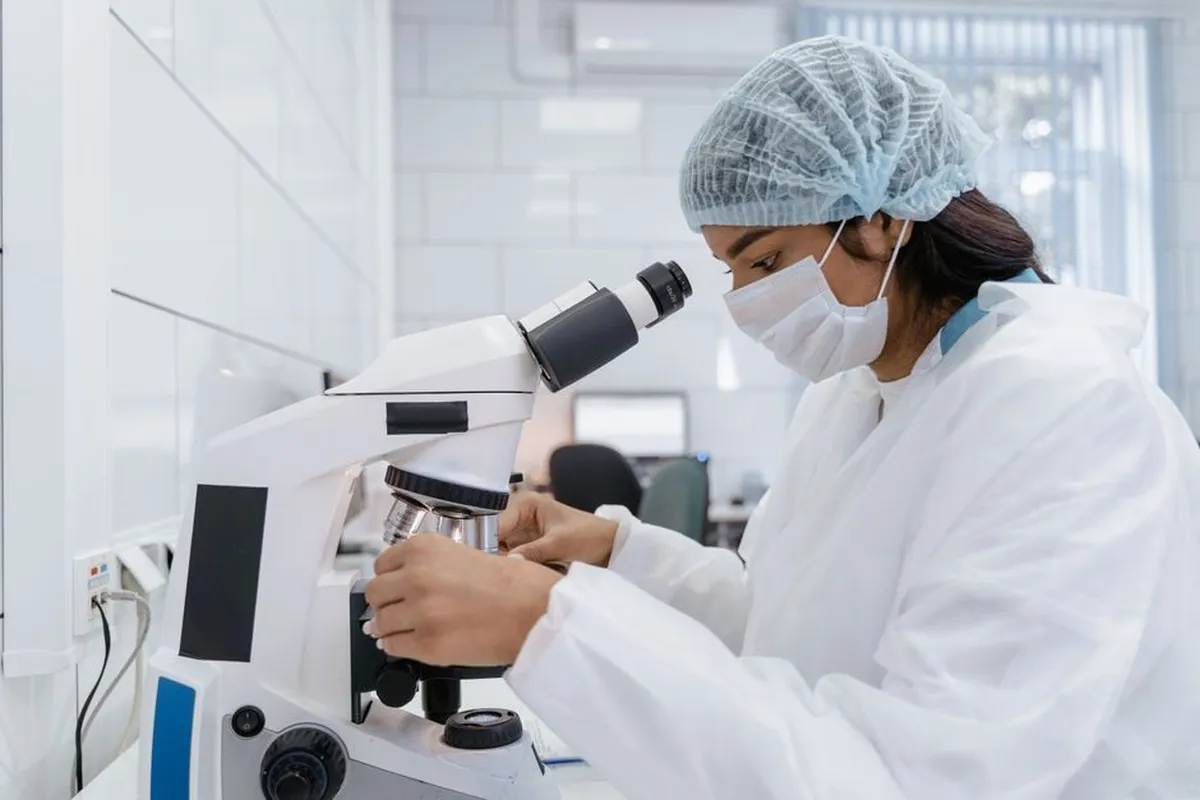 Pesquisadora concentrada trabalhando em bancada de laboratório universitário