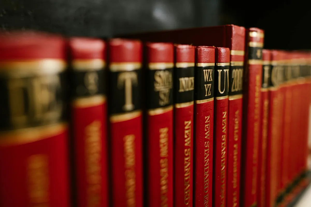 Livros acadêmicos e caderno de anotações com referências bibliográficas em mesa de estudos