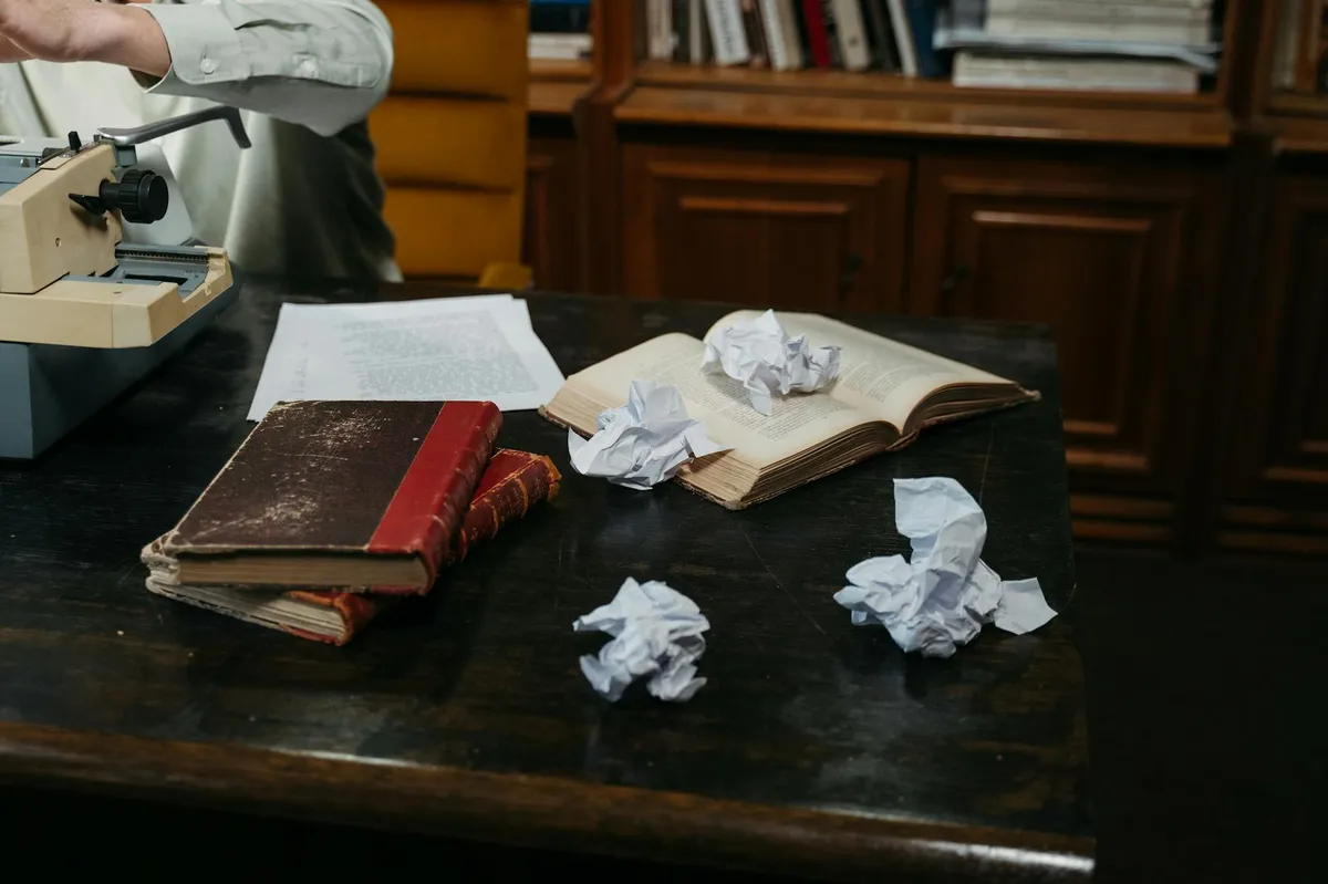 Pilha de artigos científicos e livros sobre mesa de pesquisadora com caneta ao lado