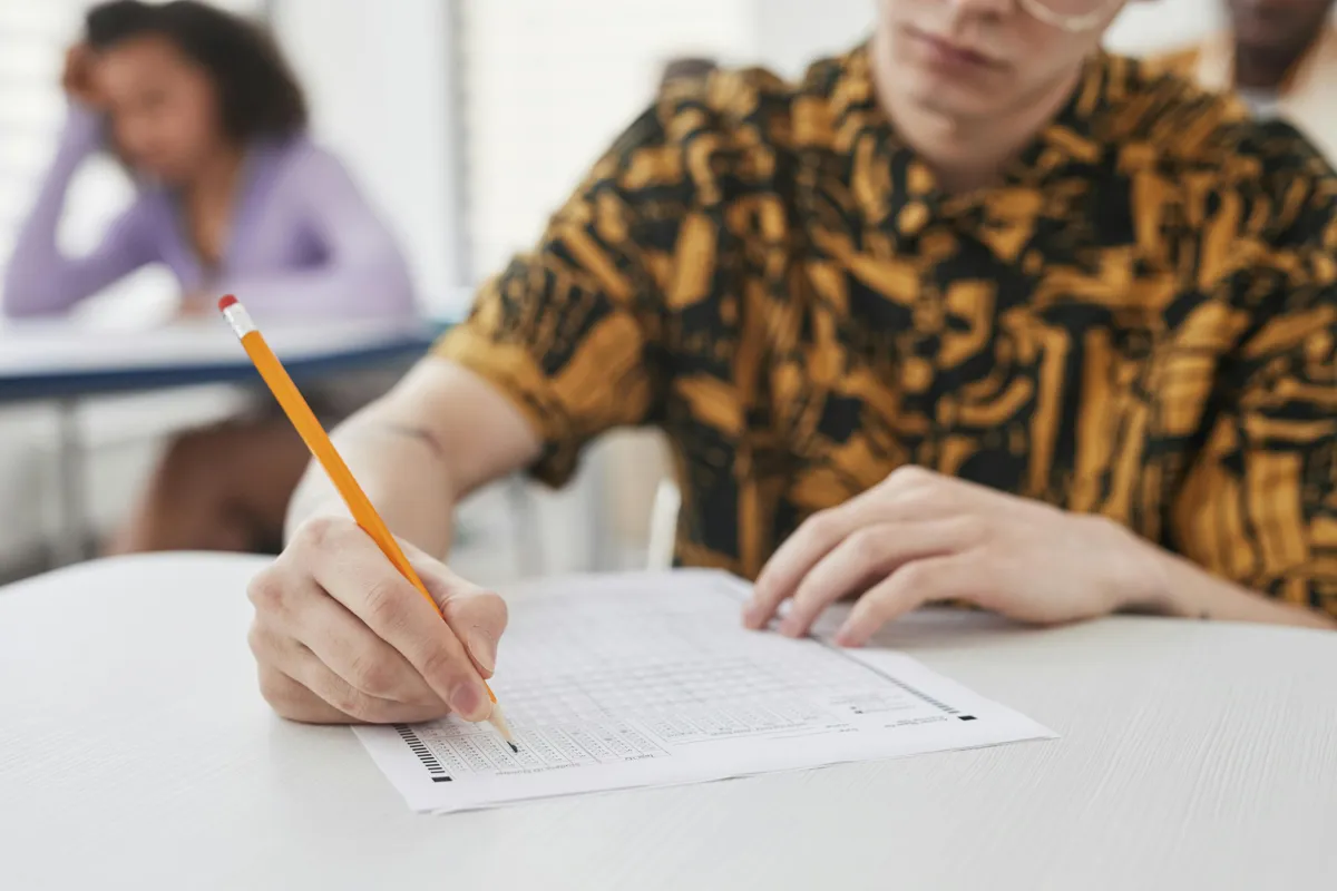 Pessoa organizando páginas impressas de um trabalho acadêmico sobre mesa de estudo.