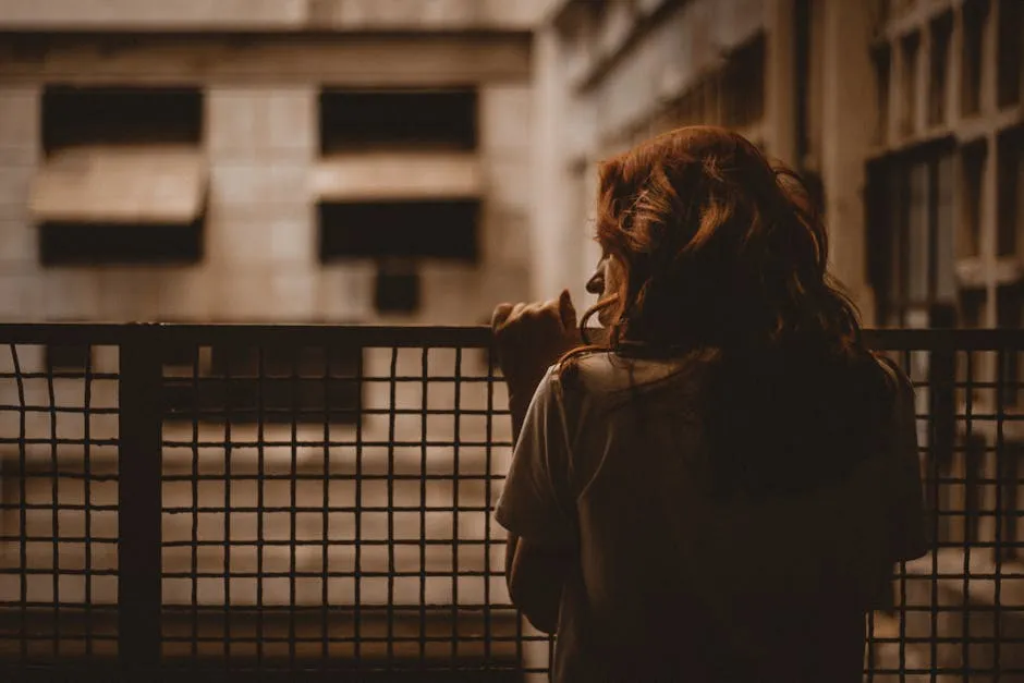 Pessoa sentada em uma escada olhando para longe, pensativa, com luz suave ao fundo