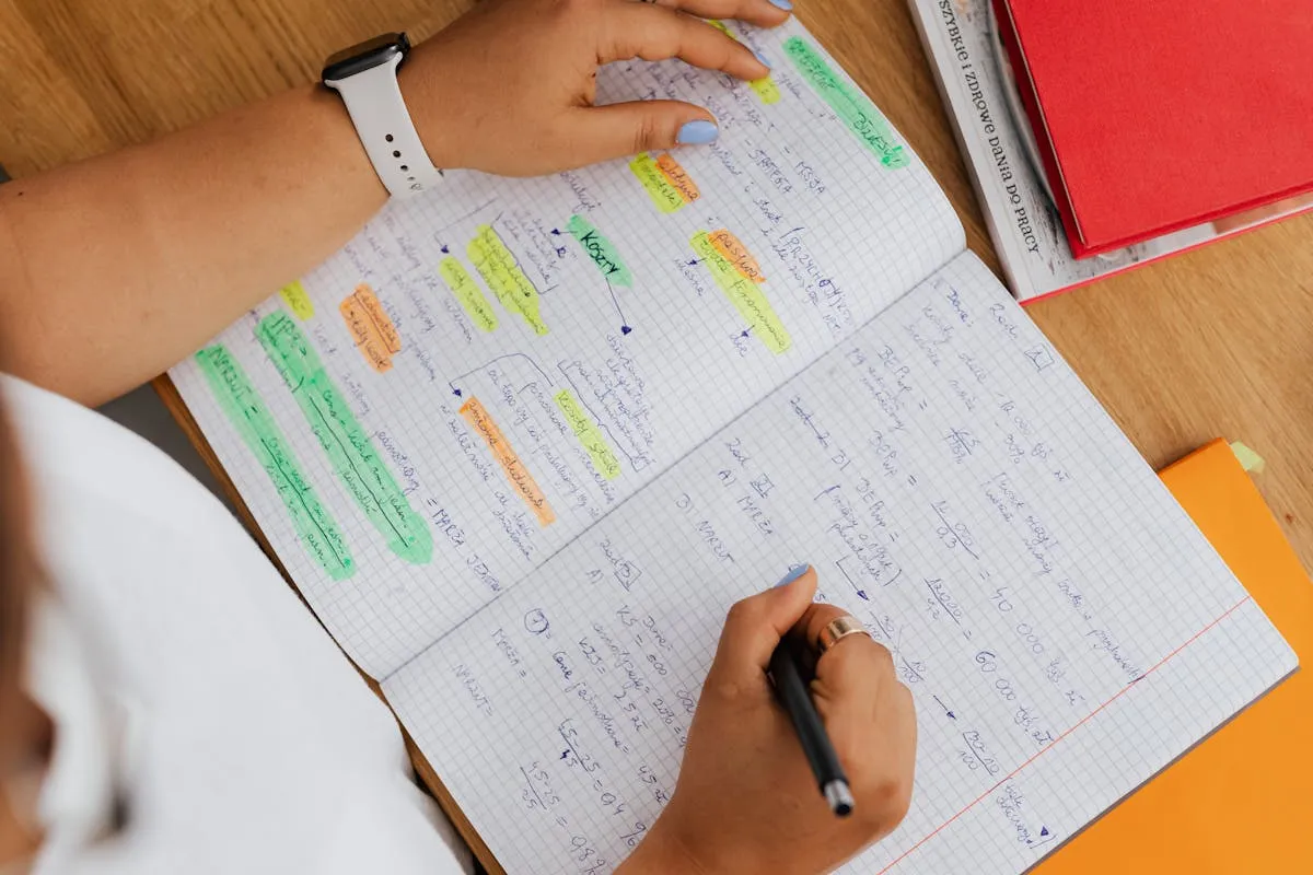 Livros empilhados com marcadores de texto coloridos sobre uma mesa de estudos universitários