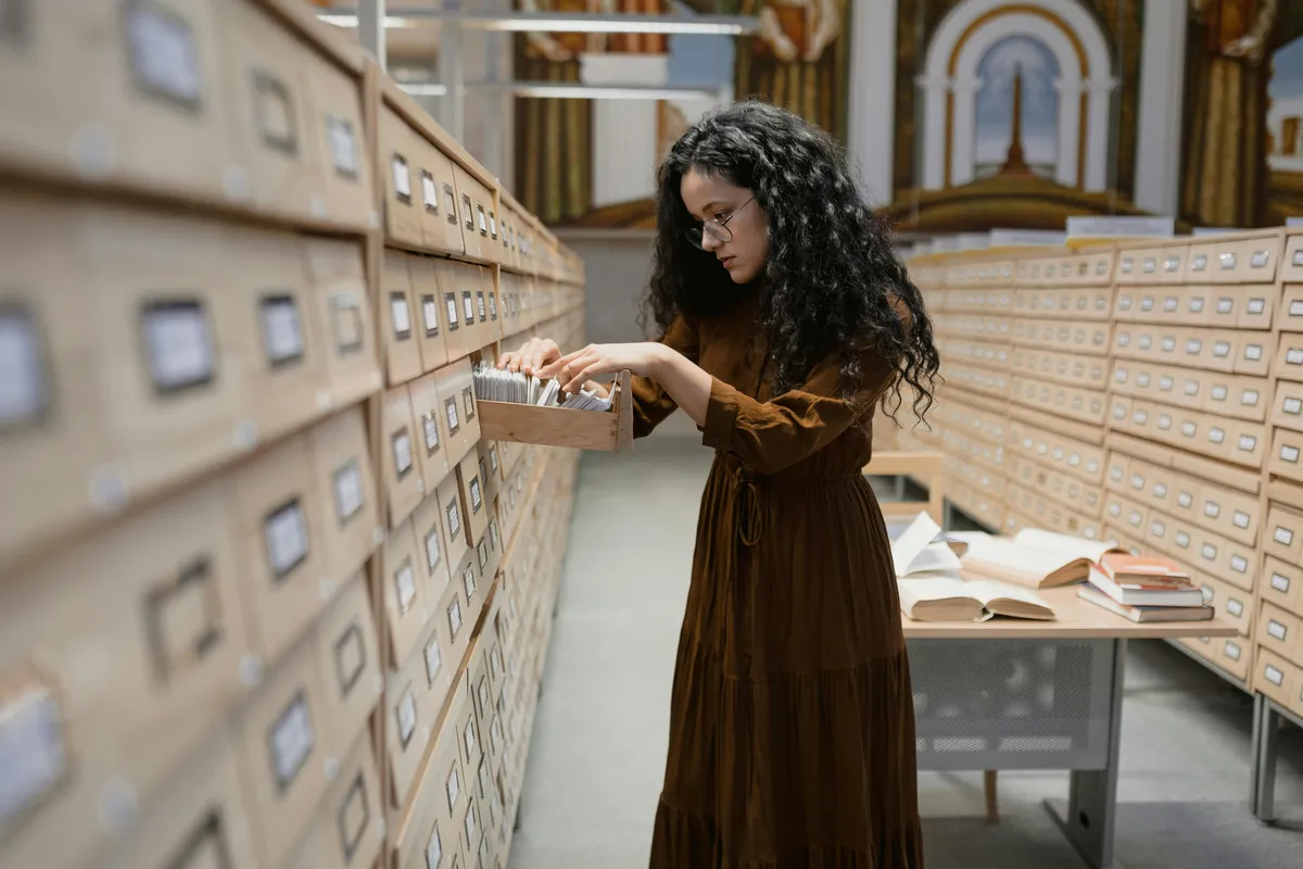 Pesquisadora analisando documentos e arquivos históricos em uma biblioteca