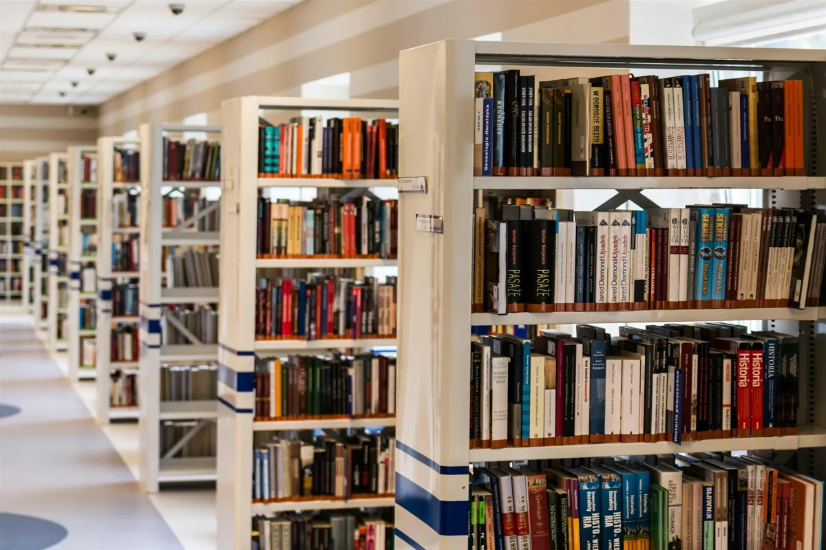 Pesquisadora em biblioteca universitária lendo documentos acadêmicos sobre educação