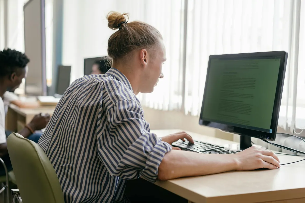 Estudante usando computador com interface de IA para trabalho acadêmico