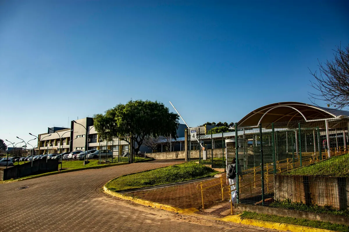 Campus universitário com área verde e estudantes caminhando, representando universidade no interior
