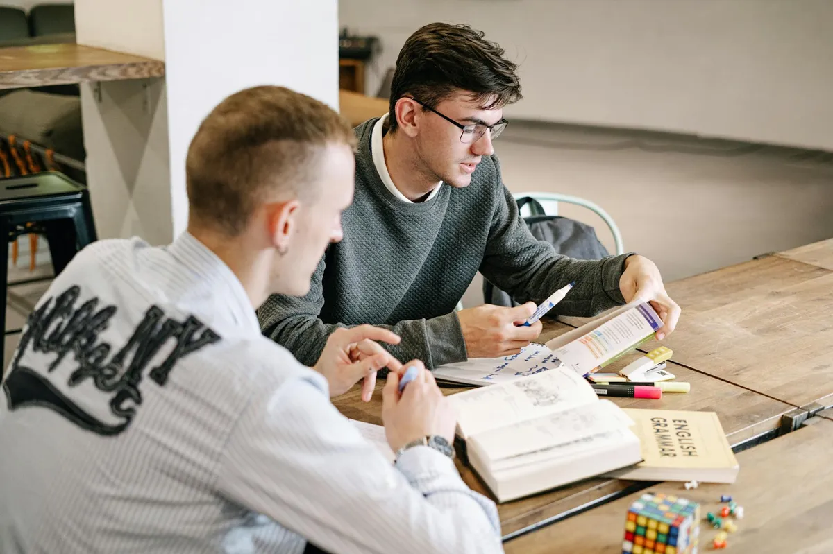 Pessoa estudando inglês com livros e anotações em mesa de estudos