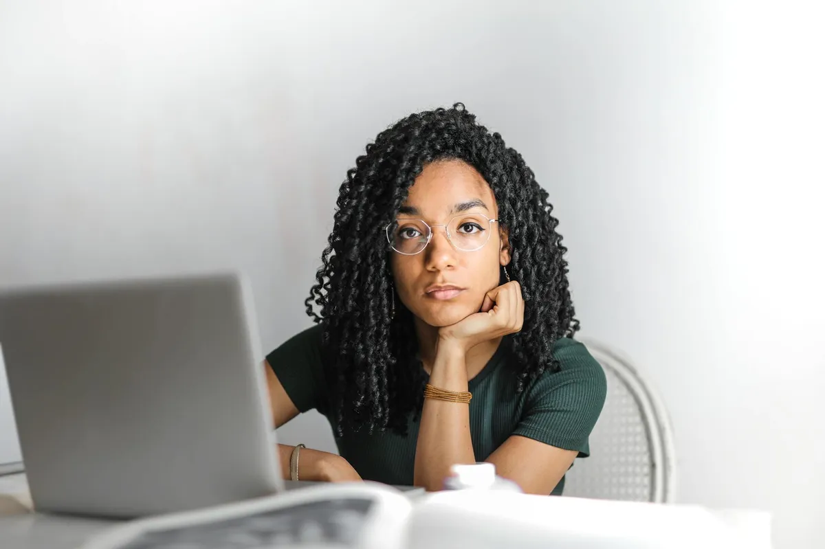 Pesquisadora lendo e-mail no computador com expressão concentrada, representando o momento de receber informações sobre a defesa