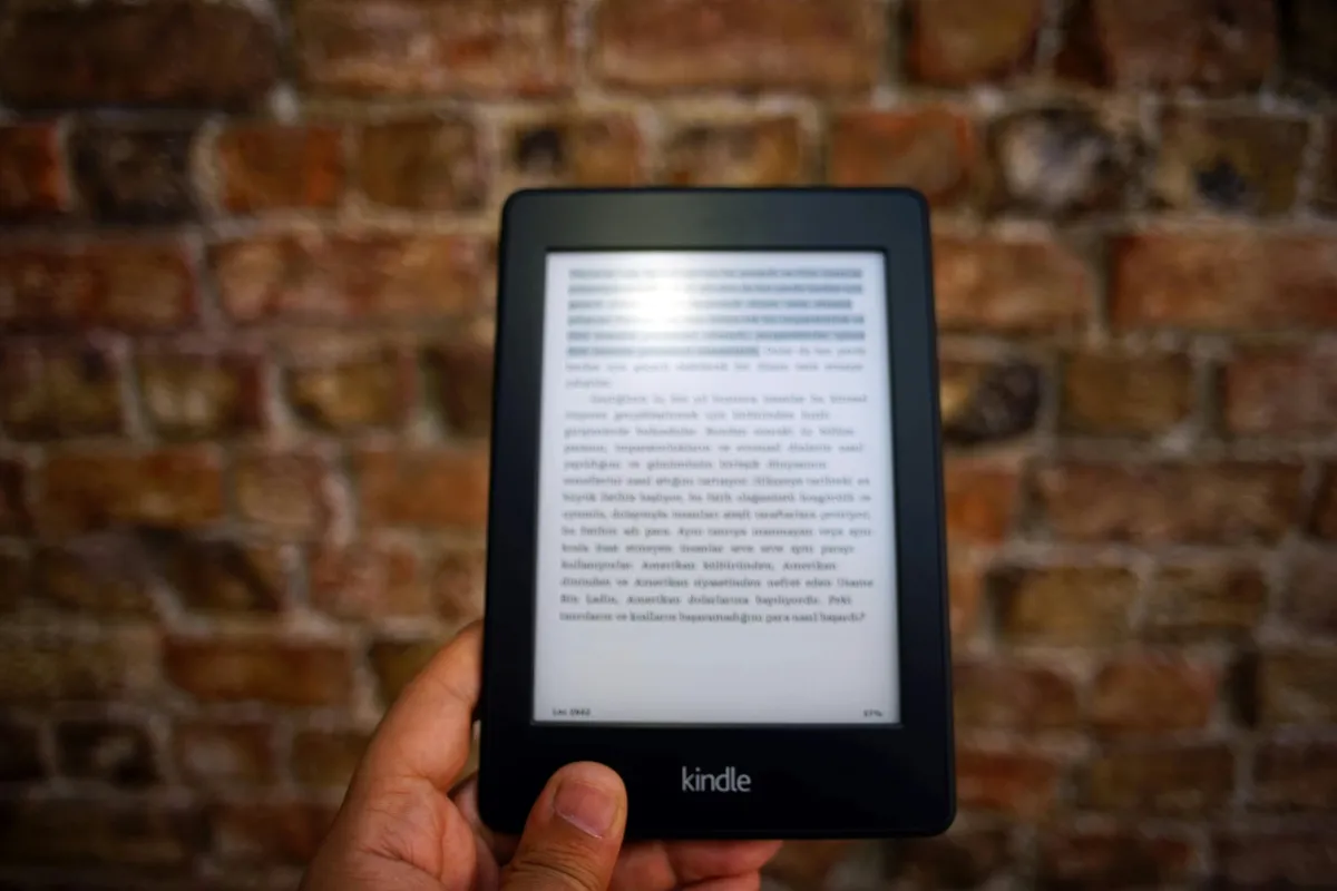 Tablet exibindo livro digital sobre mesa com caderno de anotações.