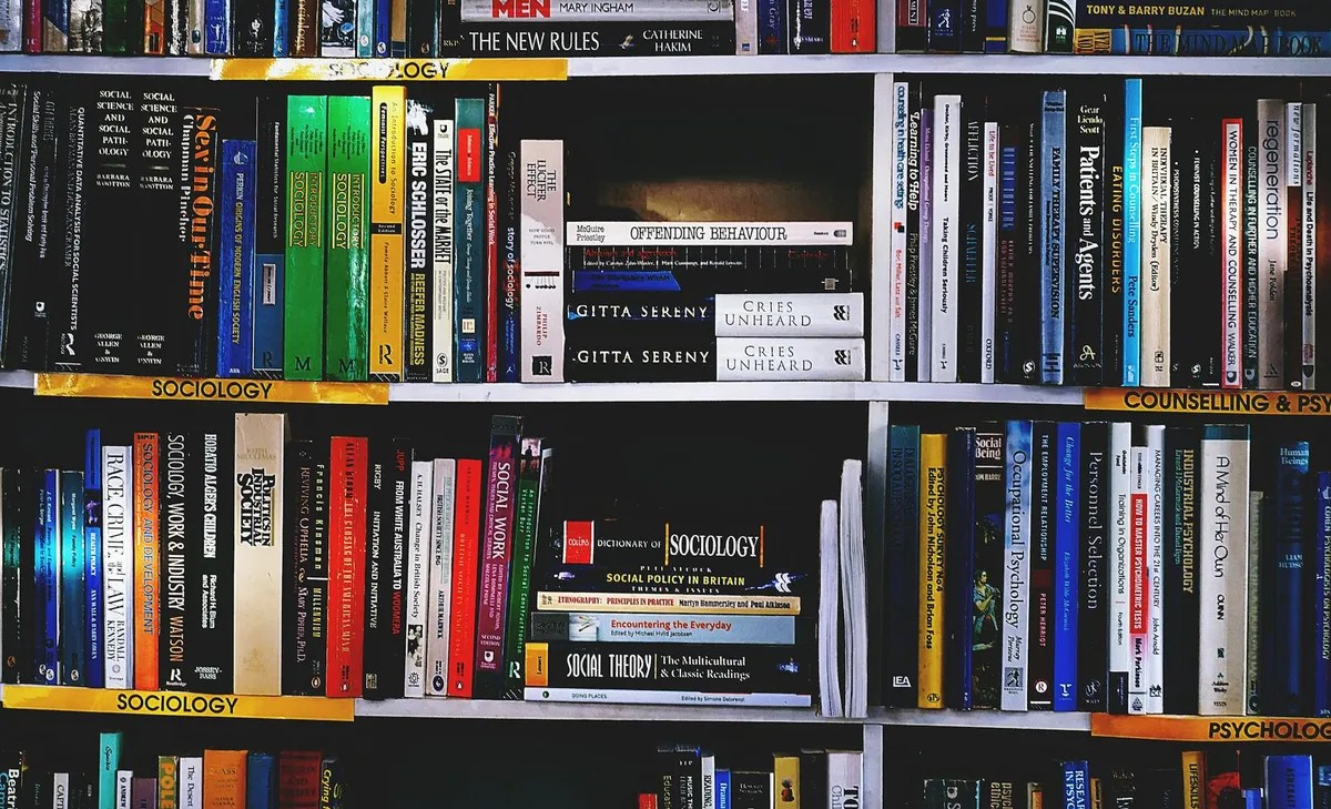 Pilha de livros abertos sobre mesa com anotações e marcadores coloridos