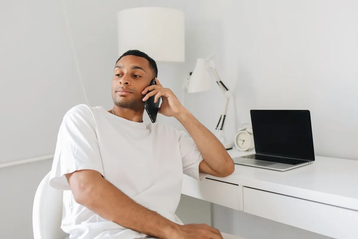 Pessoa ao telefone com notebook e agenda na mesa, representando conciliação entre trabalho e pós-graduação