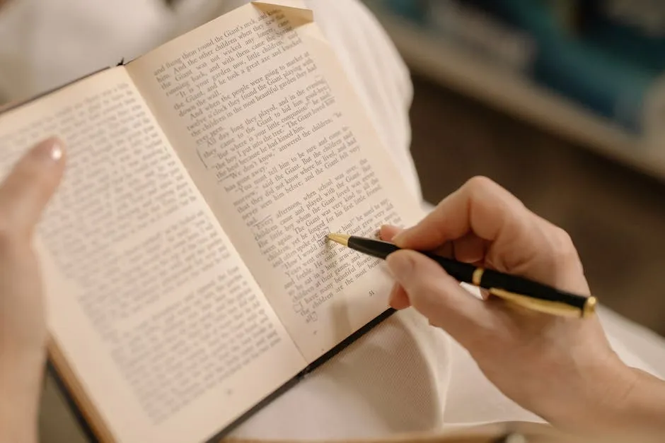 Pessoa lendo livro aberto com caderno de anotações ao lado