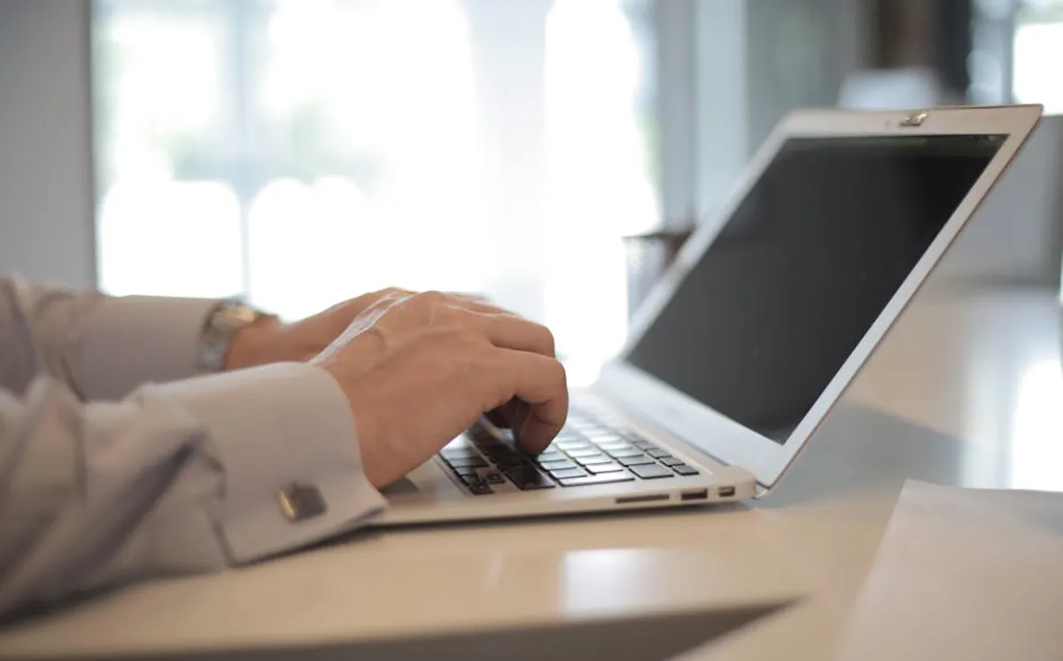 Pesquisadora digitando em laptop em mesa de escritório acadêmico