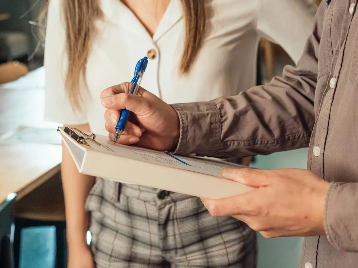 Estudante com checklist verificando formatação de trabalho acadêmico nas normas ABNT