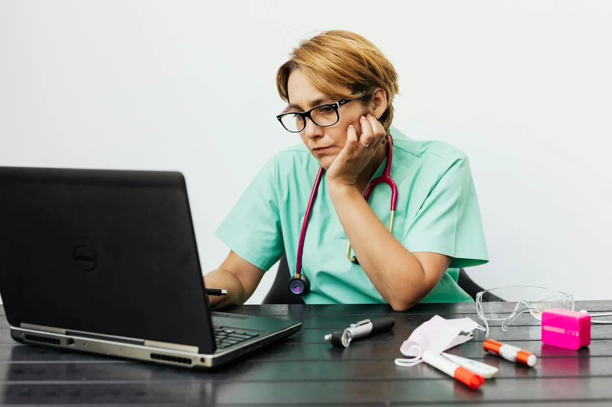 Enfermeira estudando artigos científicos em laptop em ambiente hospitalar