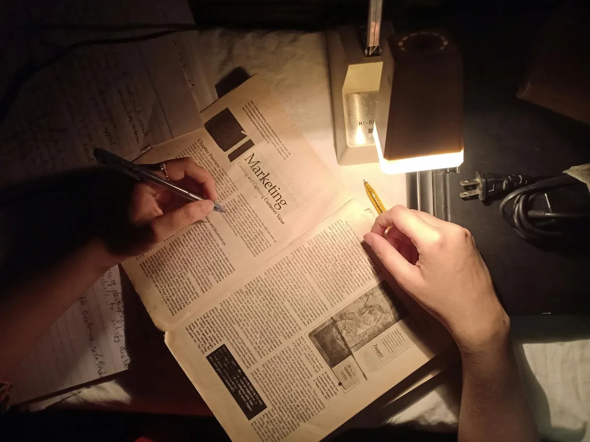 Pesquisadora lendo artigos científicos impressos em mesa de trabalho acadêmico