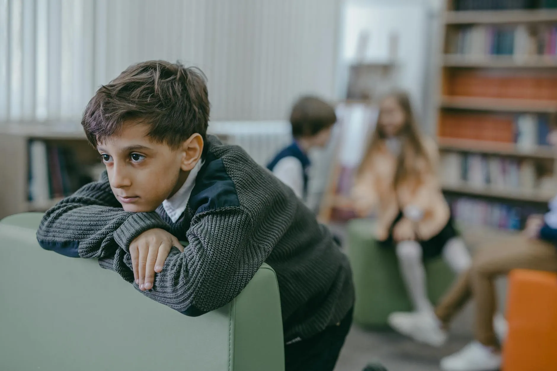 Pessoa estudando sozinha em biblioteca com pilhas de livros ao redor, luz de abajur