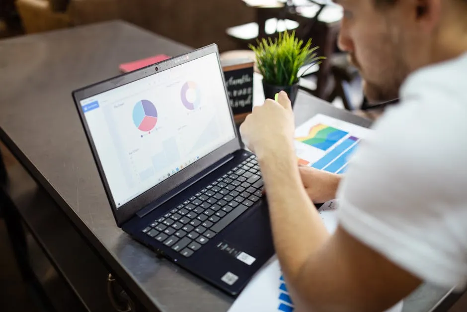 Estudante de administração trabalhando em laptop com gráficos e planilhas