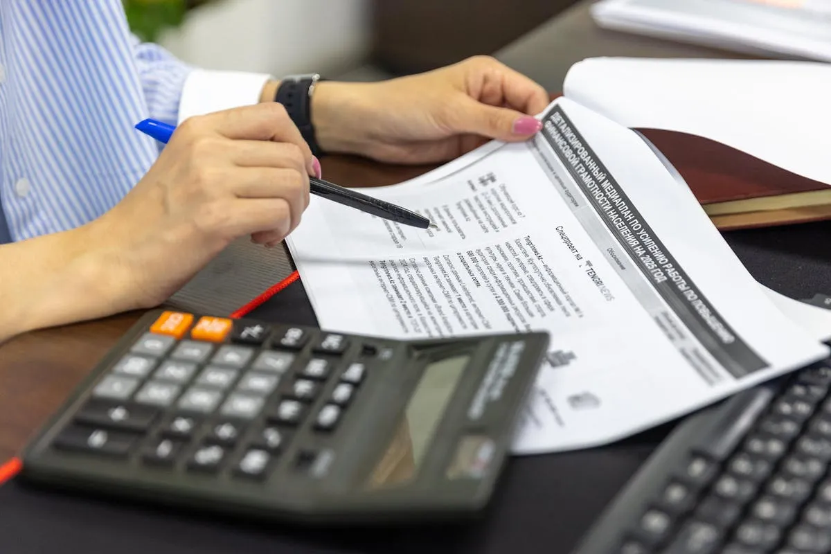 Profissional de contabilidade estudando com planilhas e livros contábeis na mesa