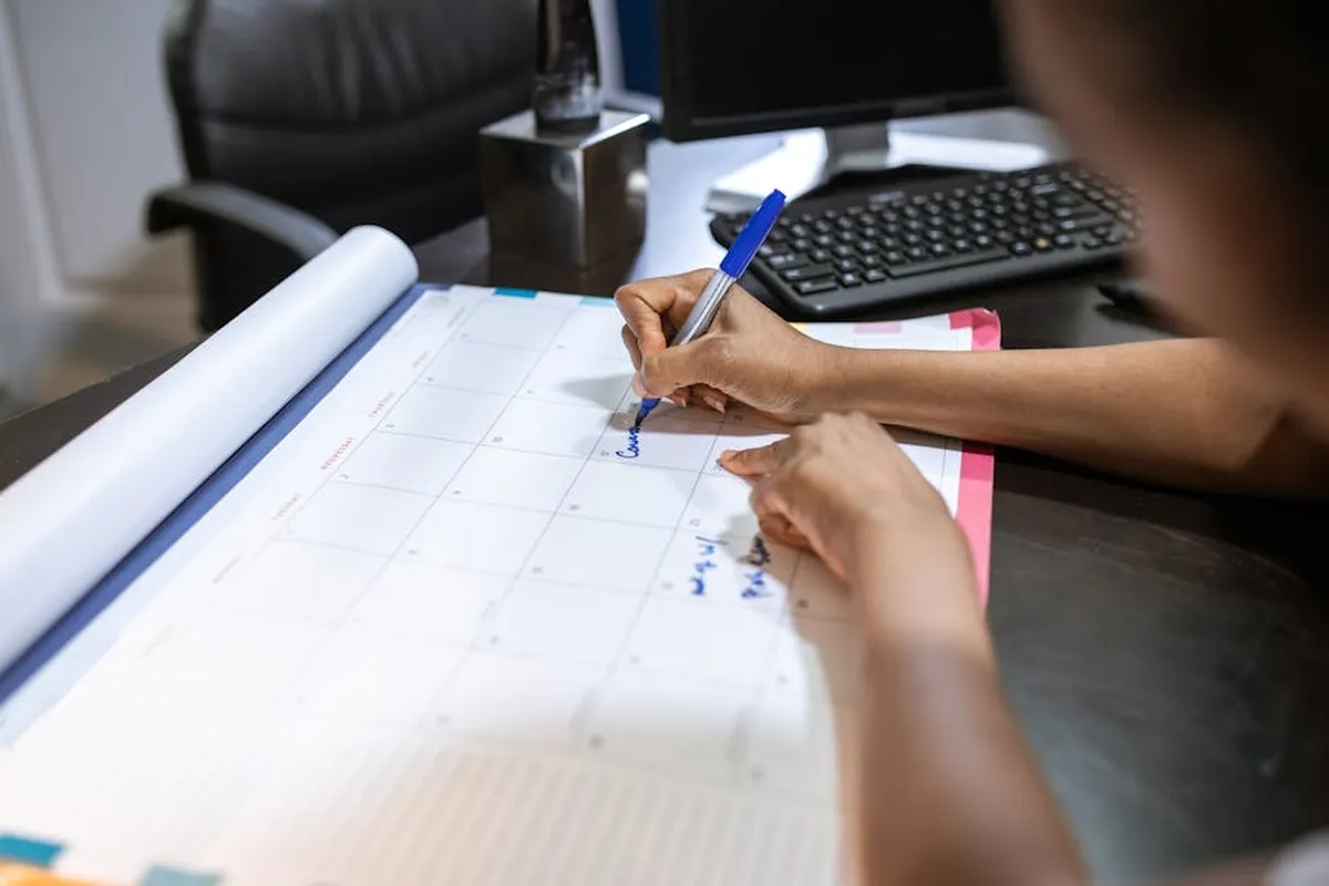 Pesquisadora aguardando resultado de avaliação de artigo com calendário e laptop na mesa
