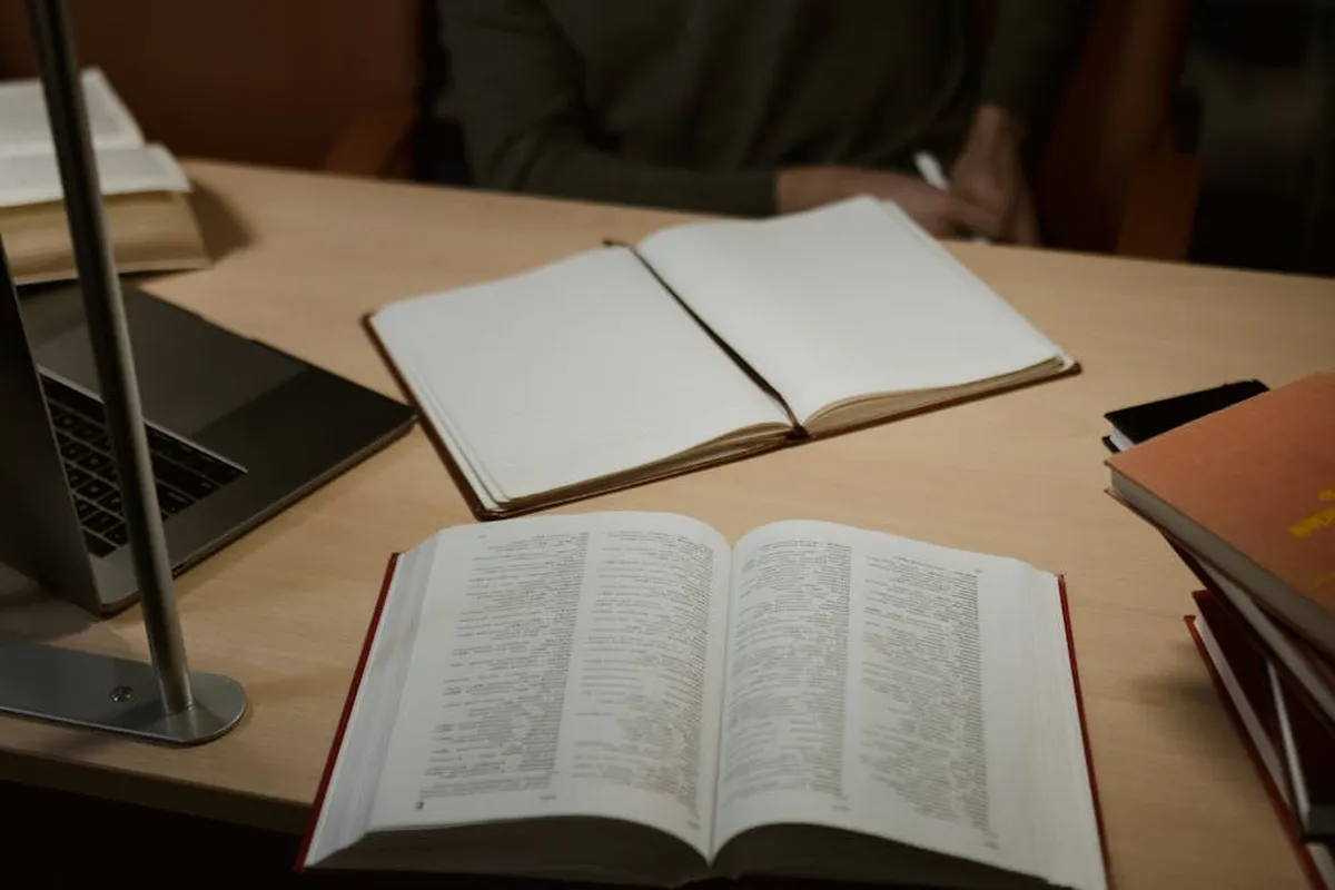 Mesa com livros abertos e caderno de anotações