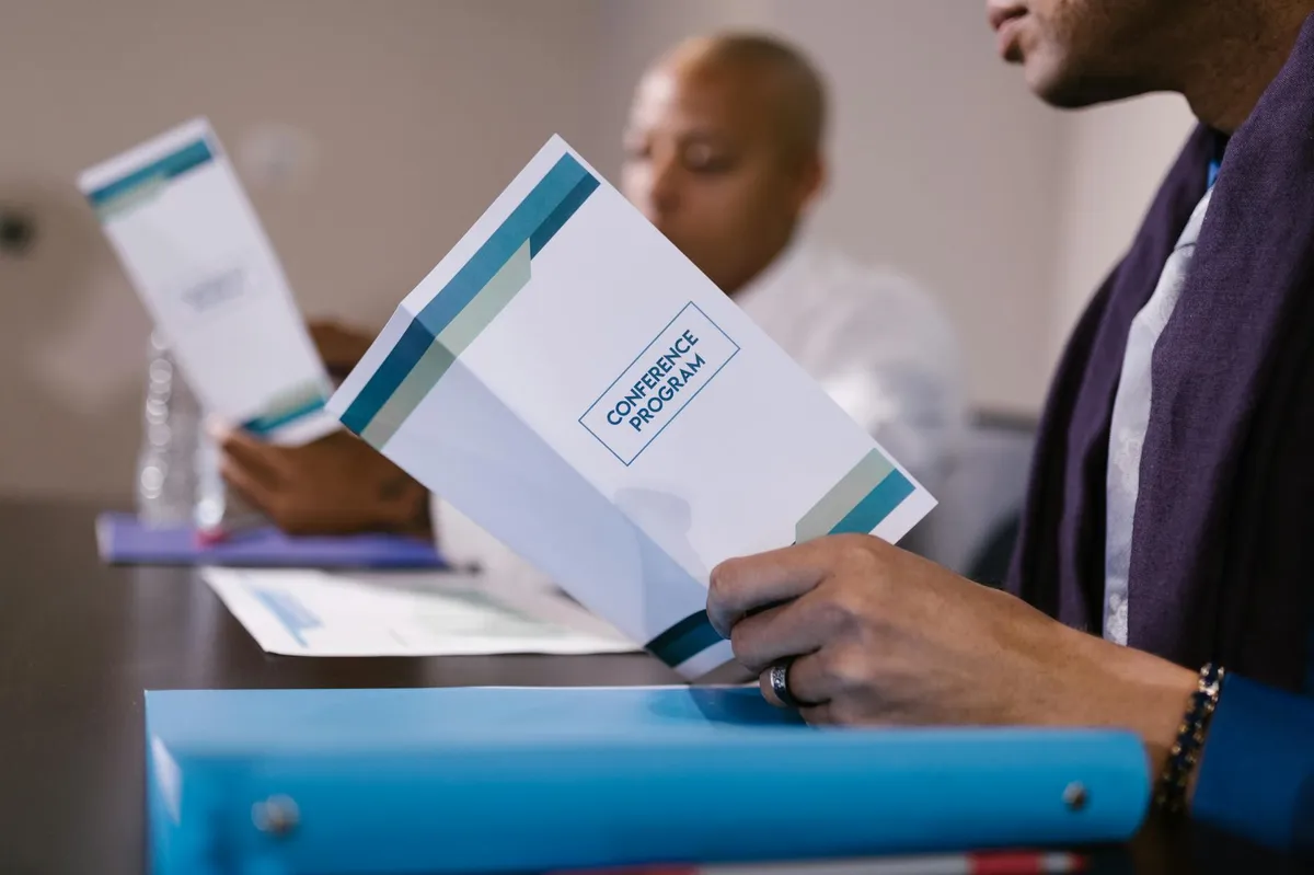 Participantes de conferência lendo programas em reunião de negócios