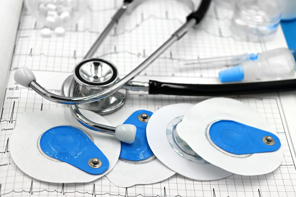 Equipamentos médicos de cardiologia com eletrodos e estetoscópio sobre traçado de ECG