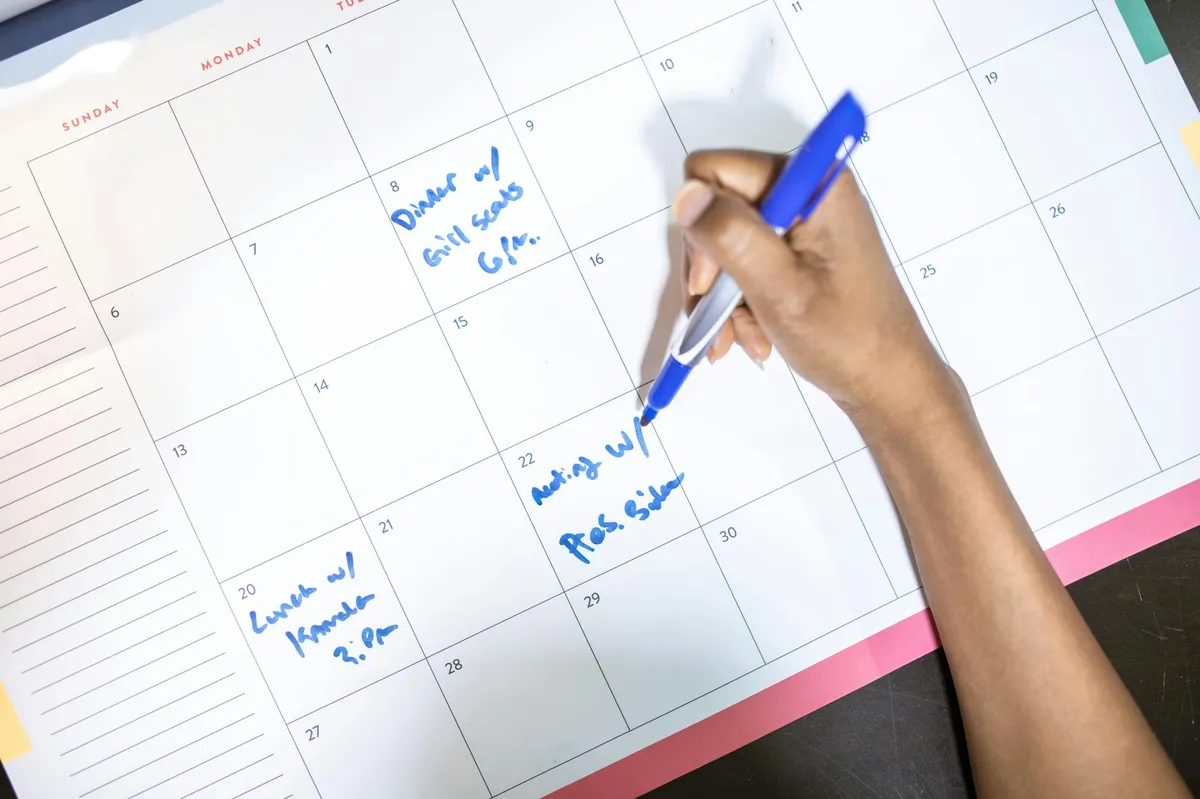 Pesquisadora analisando planilha e calendário em mesa de trabalho com caderno e laptop